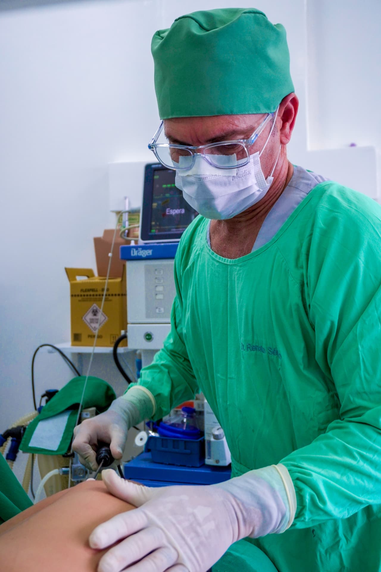 Dr. Renato Sérgio em centro cirúrgico, com equipamento de monitorização ao fundo